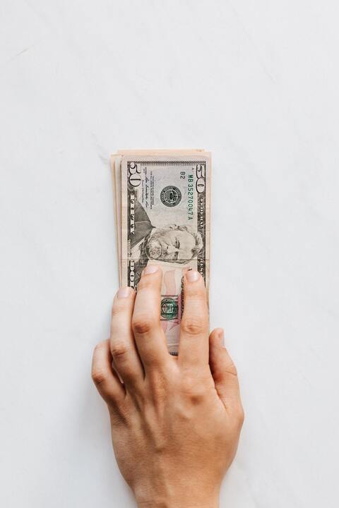 crop-unrecognizable-person-giving-heap-of-greenbacks-on-marble-table