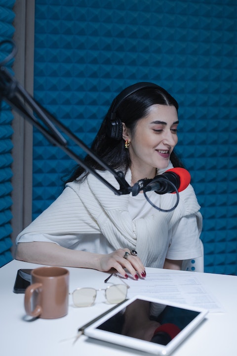 woman-in-white-shirt-sitting-beside-red-and-black-microphone