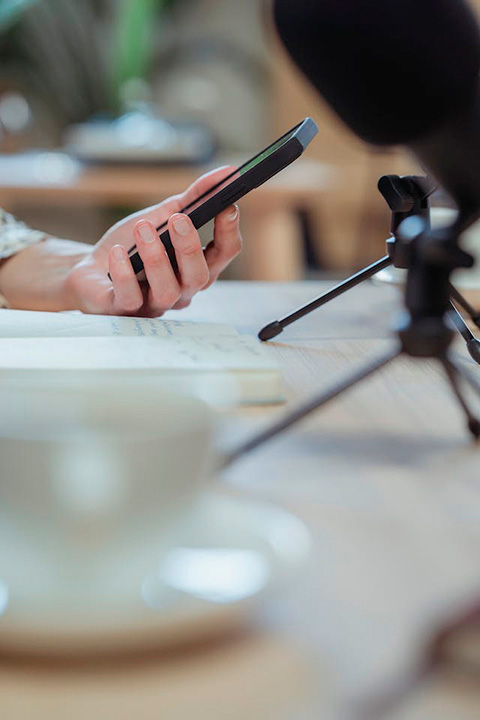 crop-unrecognizable-woman-using-smartphone-at-desk-with-microphones